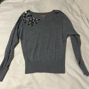Grey lightweight sweater with large sequin detail on shoulder.